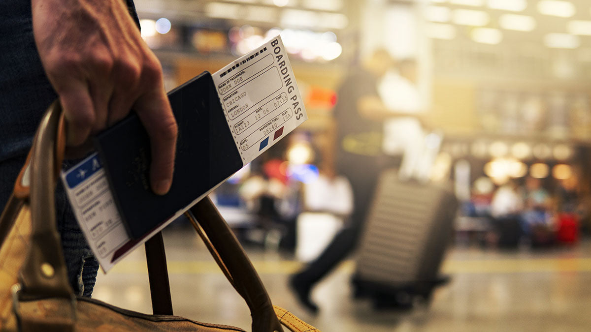 A close-up view of a hand holding essential travel documents, signifying the final preparation before approaching airport security checkpoints or boarding a flight, a moment where knowledge of unique restrictions on items like telescoping vs. folding poles is essential.