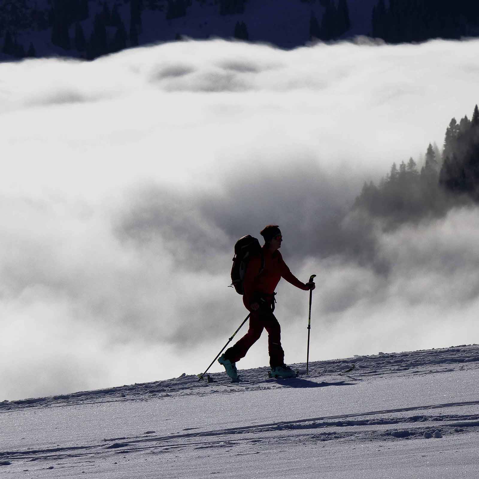 Person hiking through a snowy landscape with foggy mountains in the background